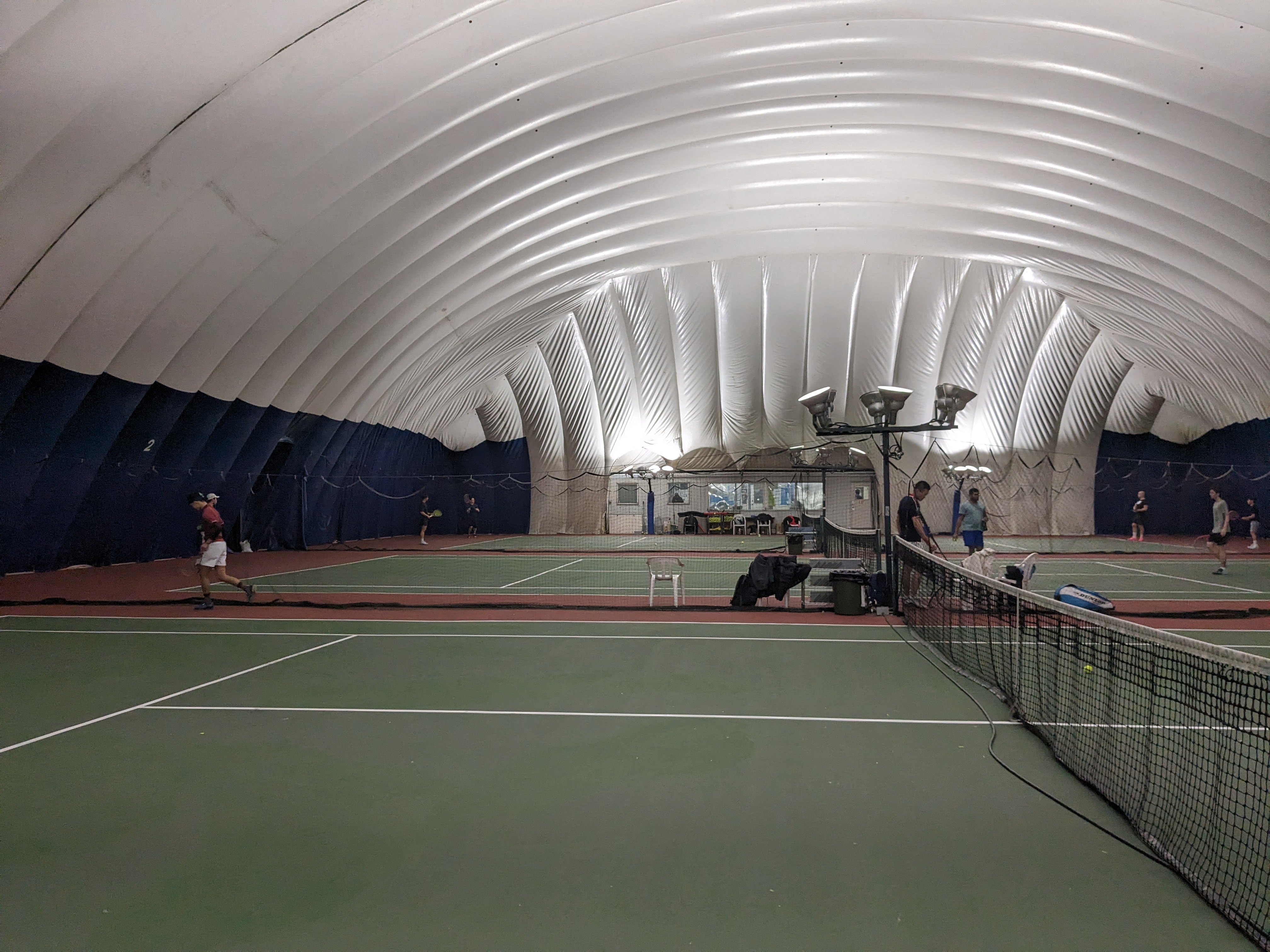 Interior of a Toronto indoor tennis bubble, with hard courts and a high inflatable fabric ceiling.